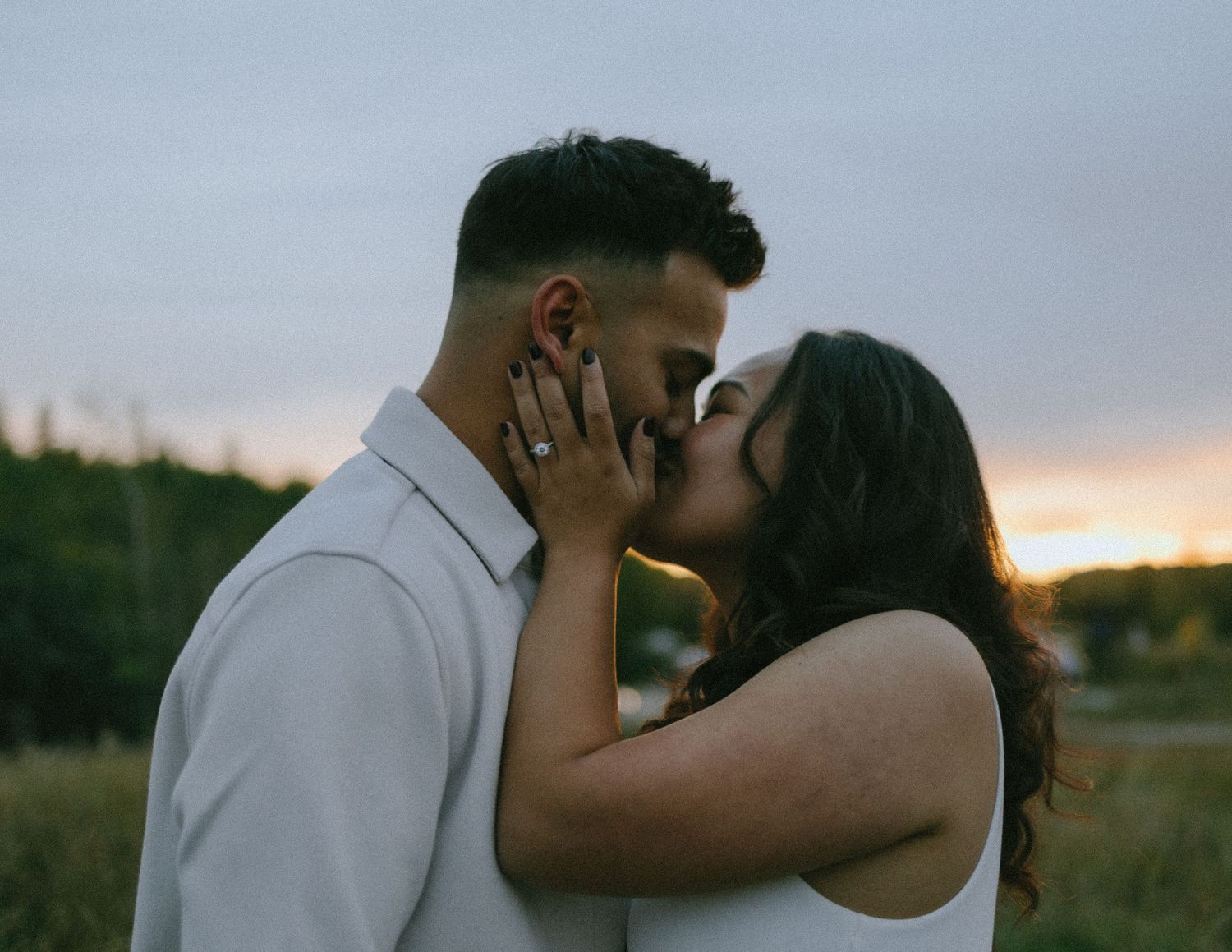 Romantic sunset portrait of a couple sharing an intimate moment in a field.