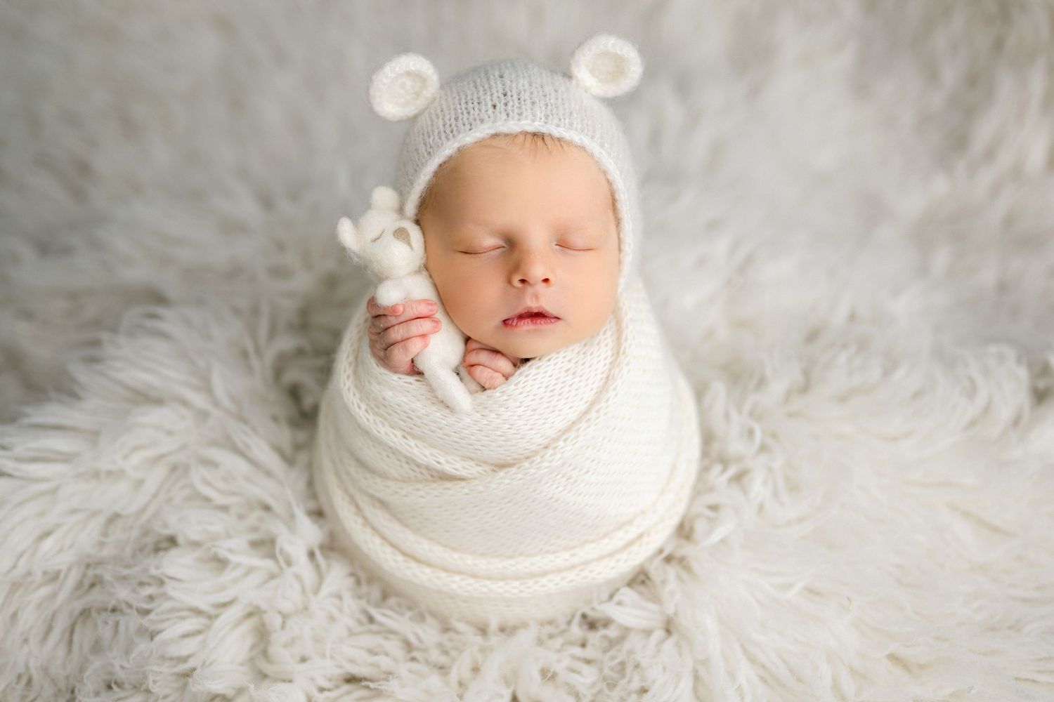 Newborn wrapped in grey swaddle sleeping in vintage metal bucket with knitted blanket.