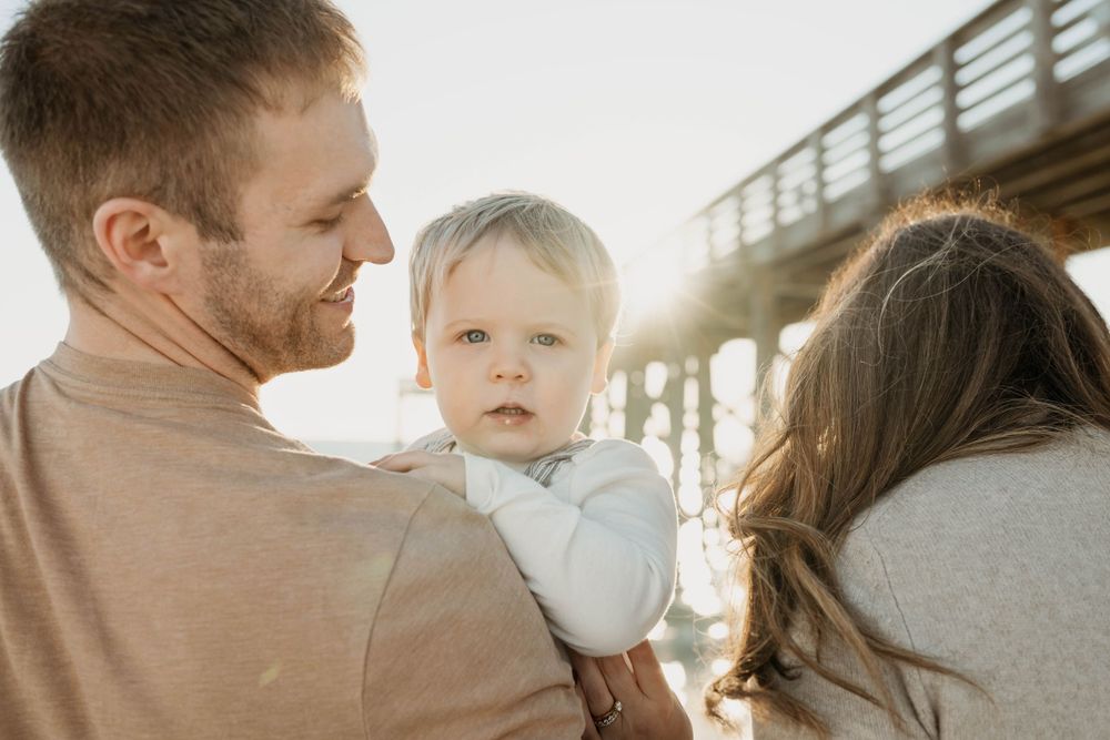 A family shares an intimate moment together at sunset near a pier.