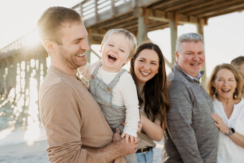 A family sharing joyful laughter together on a beach during sunset.