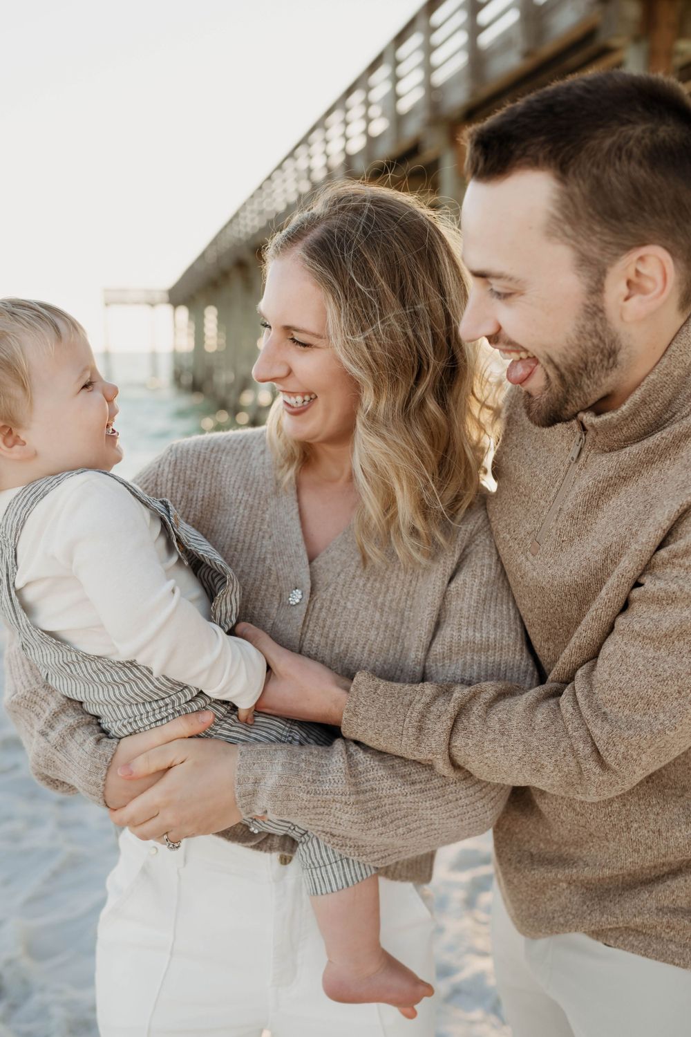 A family shares a joyful moment together on the beach wearing cozy sweaters.