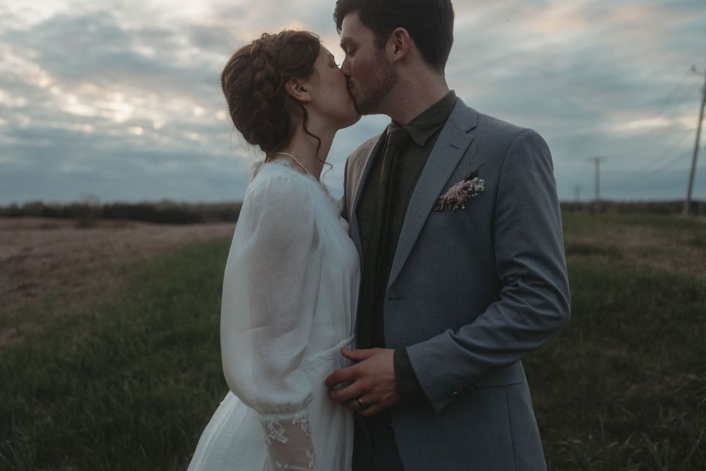 An intimate portrait of newlyweds sharing a moment at sunset in formal wedding attire.