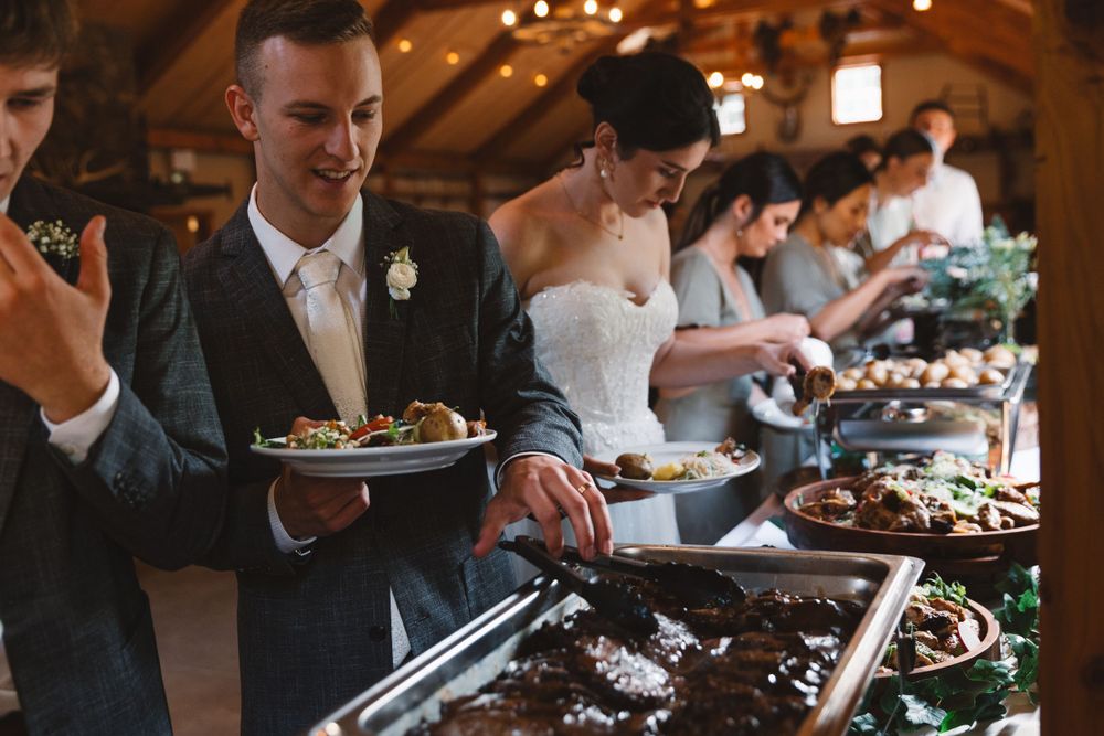 Wedding guests selecting food from catered buffet line.