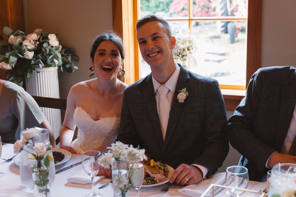 A wedding couple sits at their reception table enjoying a meal together.