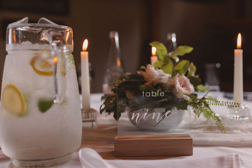 Wedding table decor featuring citrus water, table number, and floral arrangement.