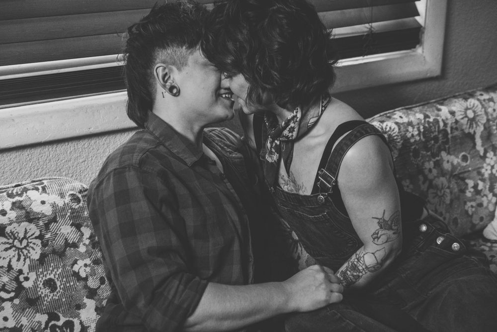 An intimate black and white portrait of a couple sharing a close moment on a floral couch.