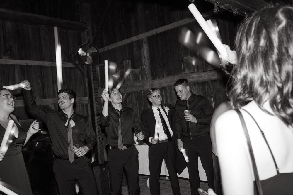 Wedding guests dancing and celebrating in black and white at an indoor reception.