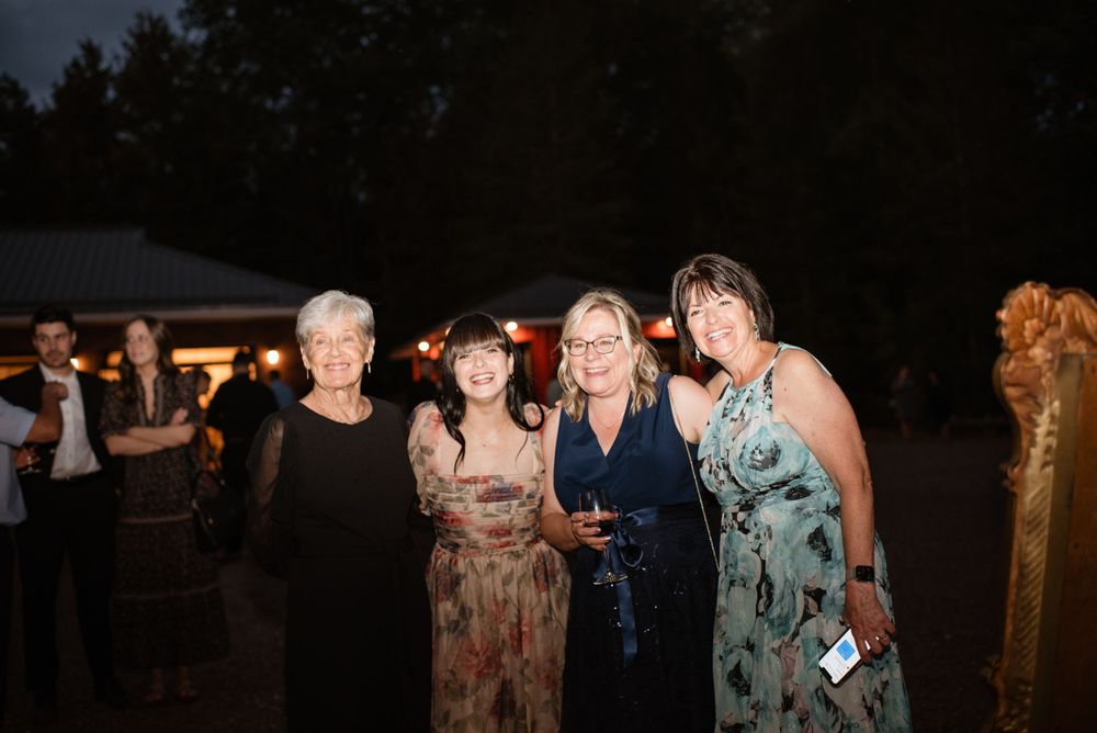 A group in formal attire poses together at an outdoor evening event with a tent visible in the background.