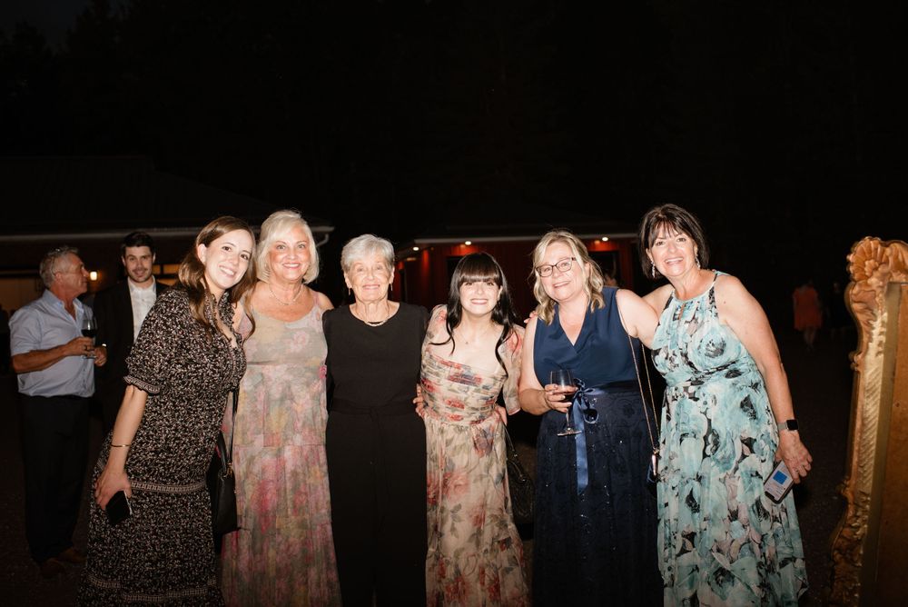 A group of women in evening dresses standing together at a nighttime event.