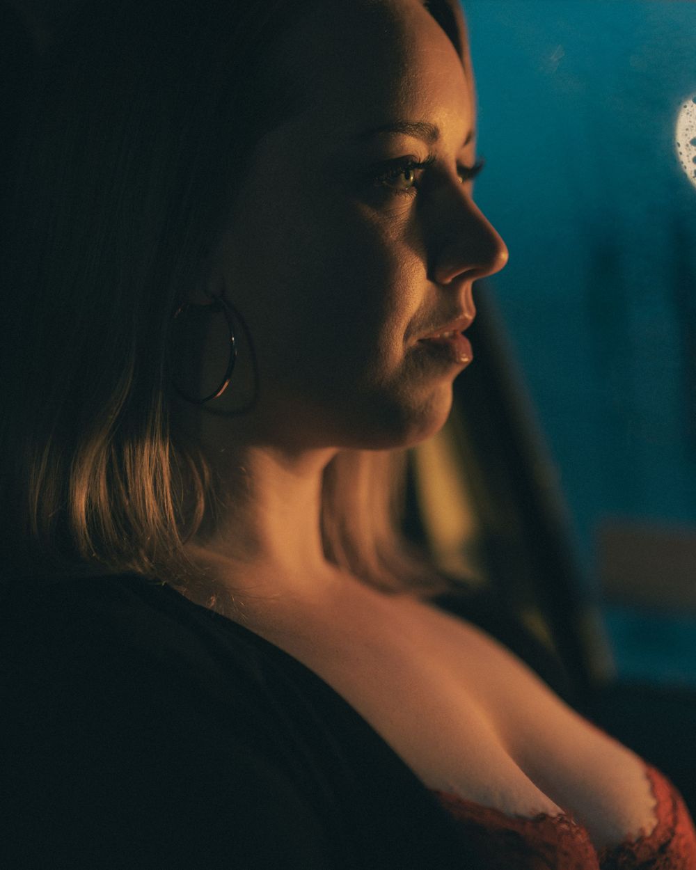 A dramatic profile portrait captured with warm lighting against a dark blue background.