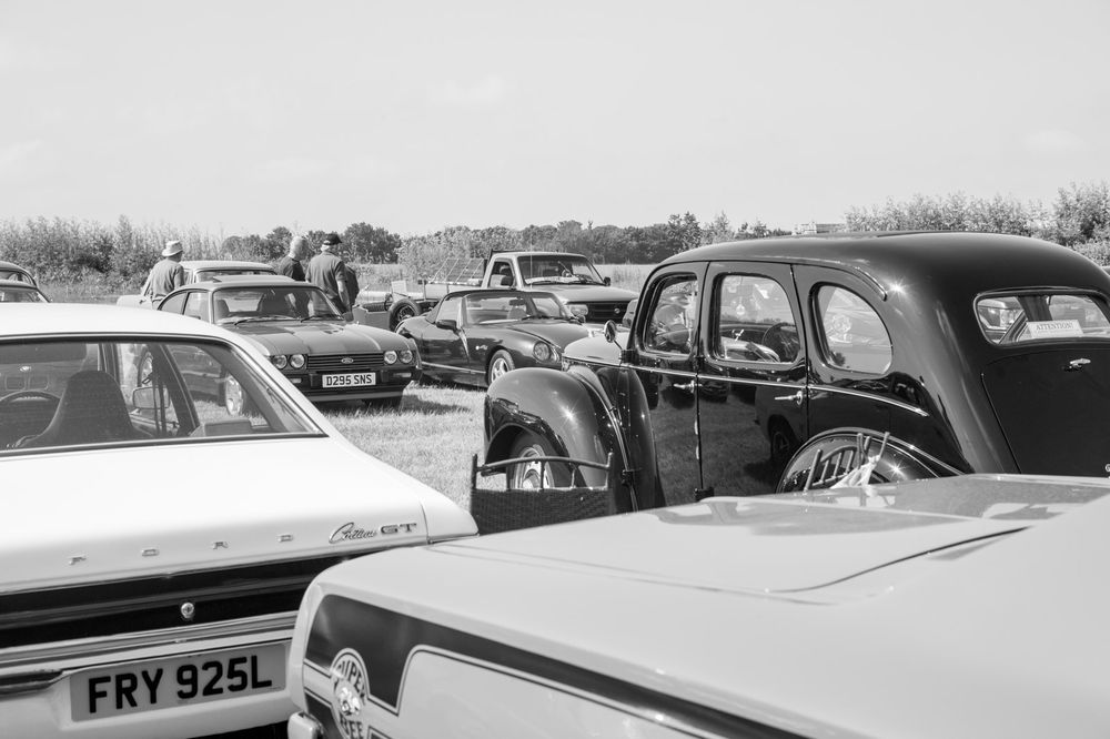 Black and white vintage car show photograph showing multiple classic automobiles parked together.