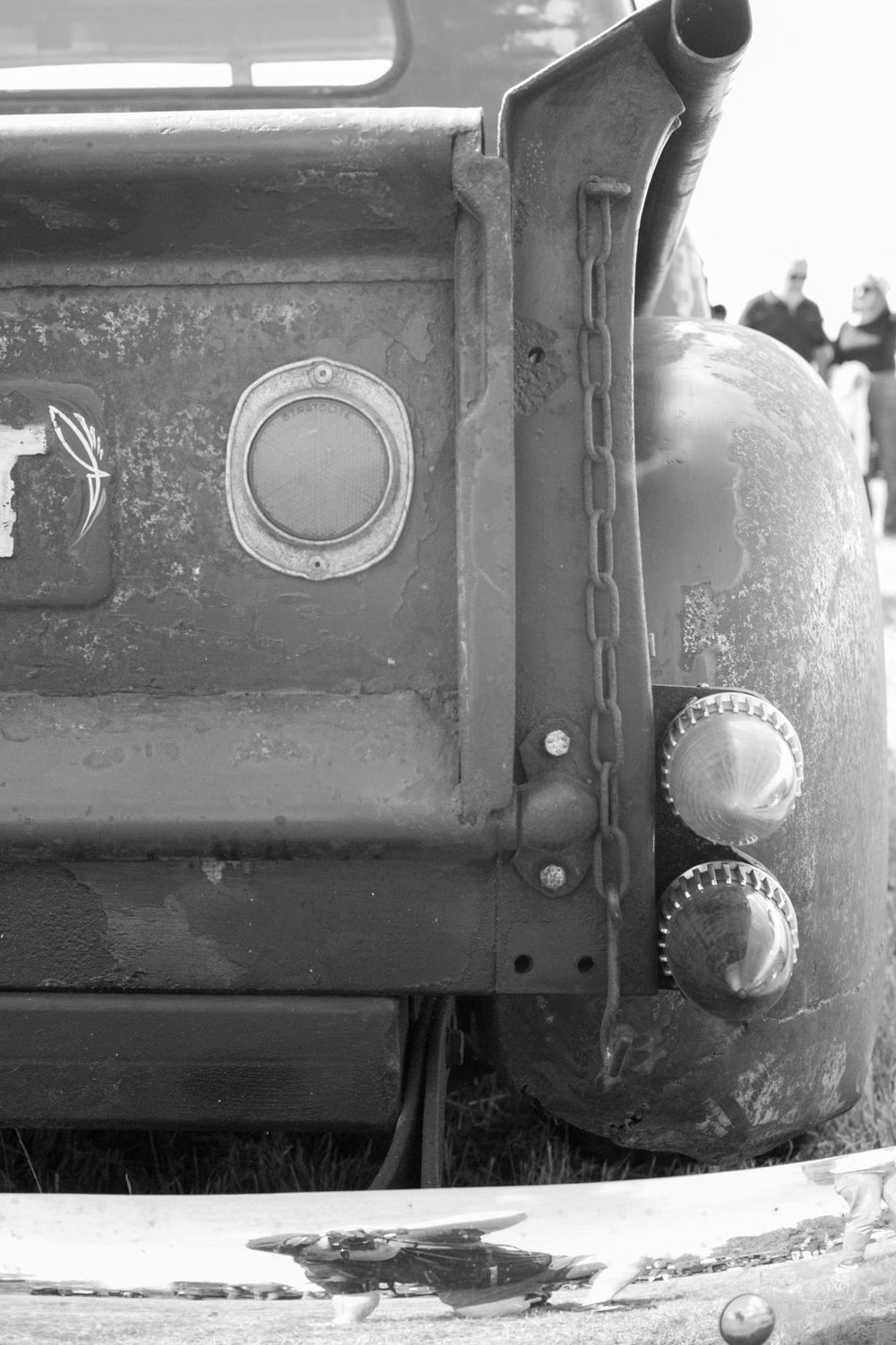 A black and white detail shot of an old truck's side panel showing worn metal knobs and port holes.