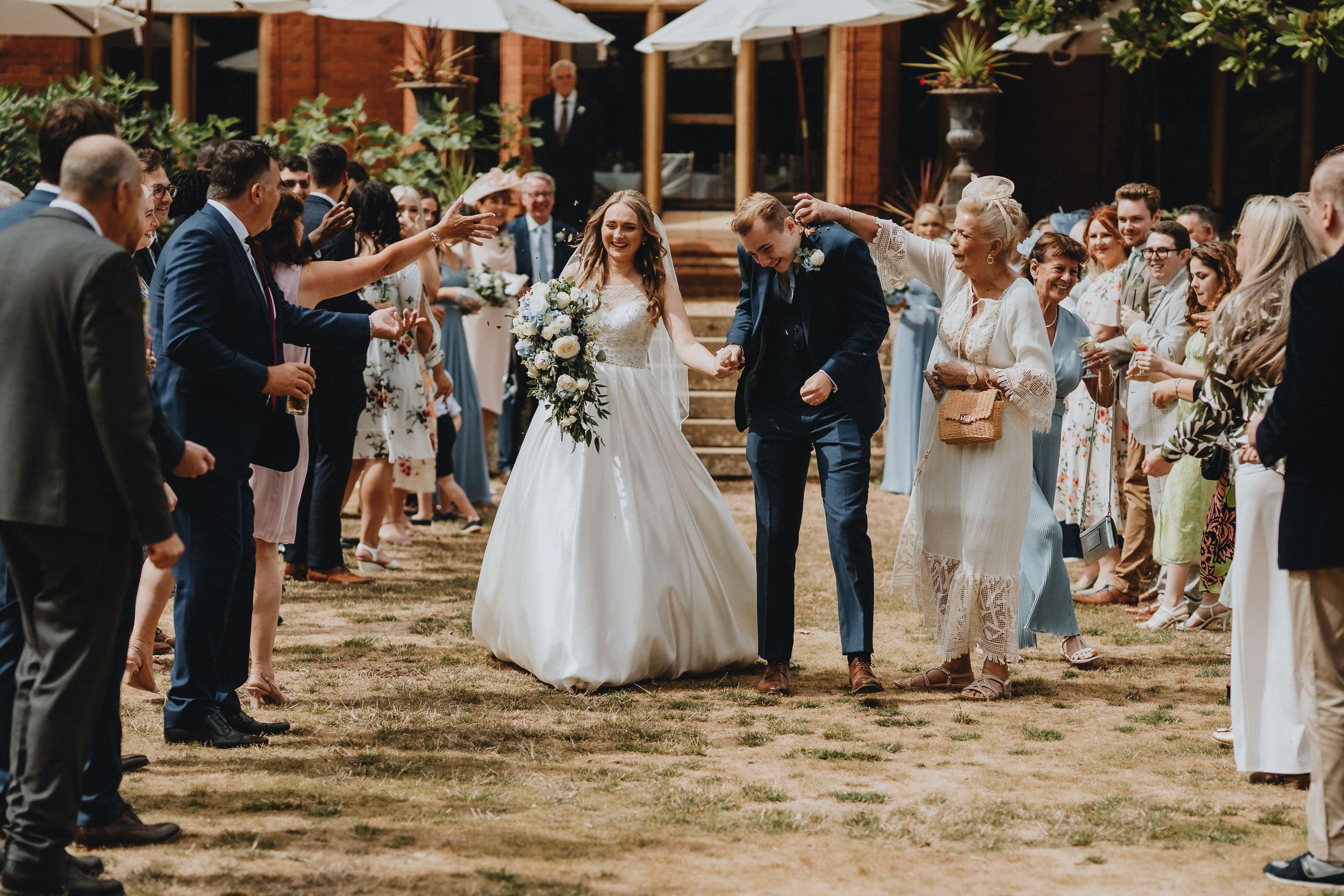 Guests gather outdoors at a rustic wedding celebration as newlyweds celebrate under clear skies and string lights.