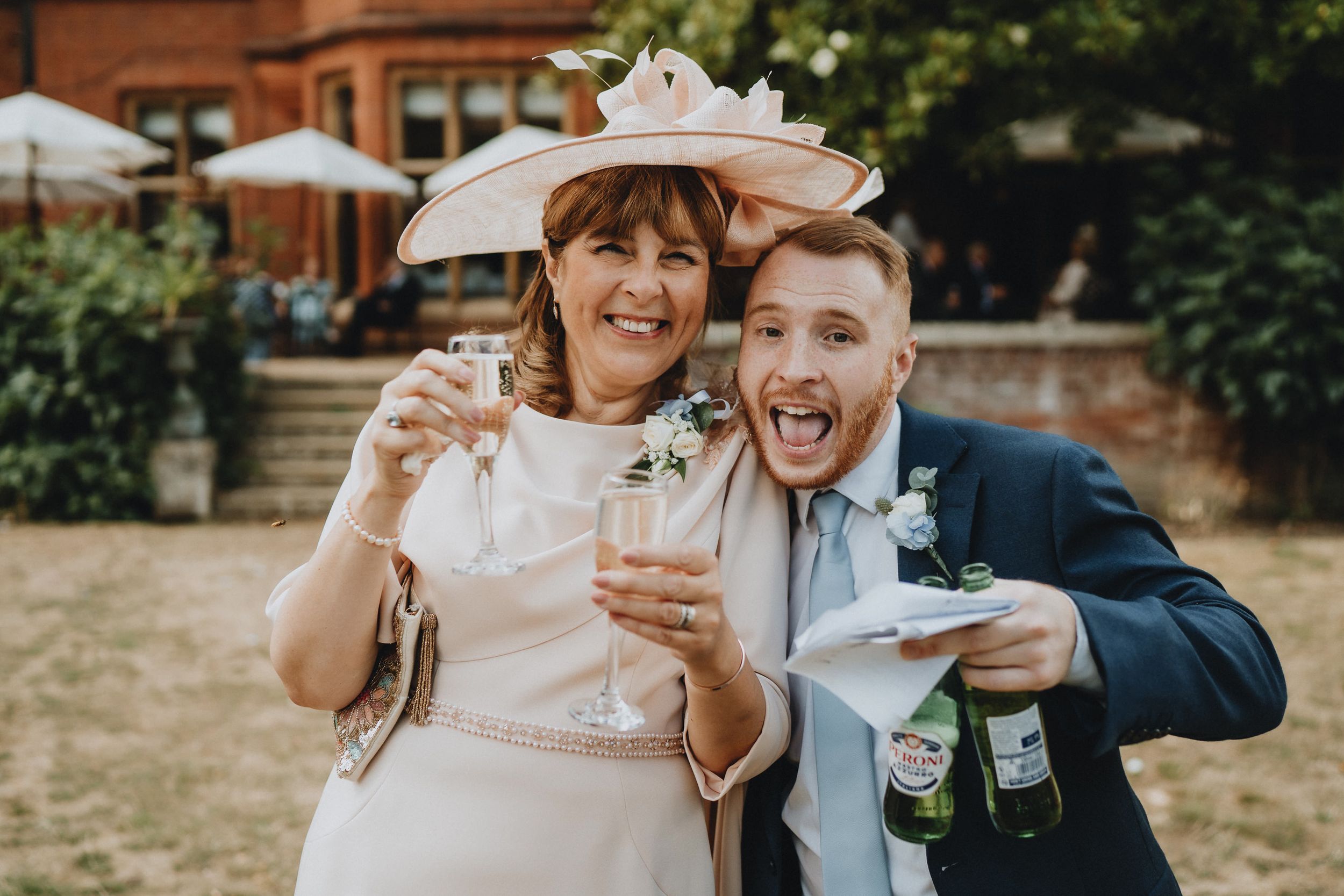 Wedding celebration with guests enjoying drinks and laughter at an outdoor garden reception.