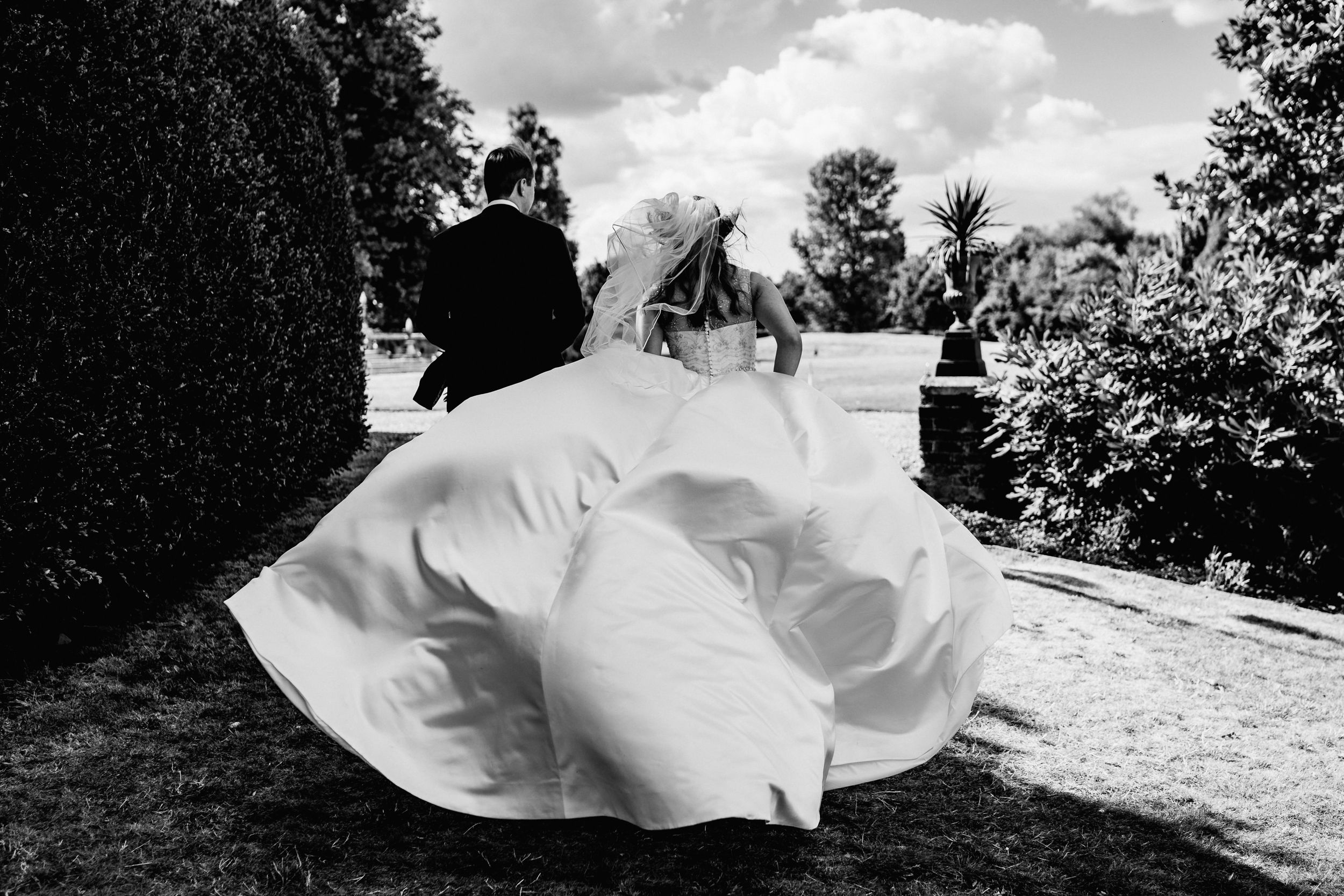 A dreamy black and white wedding scene shows a dancing couple in formal attire twirling on an outdoor patio.