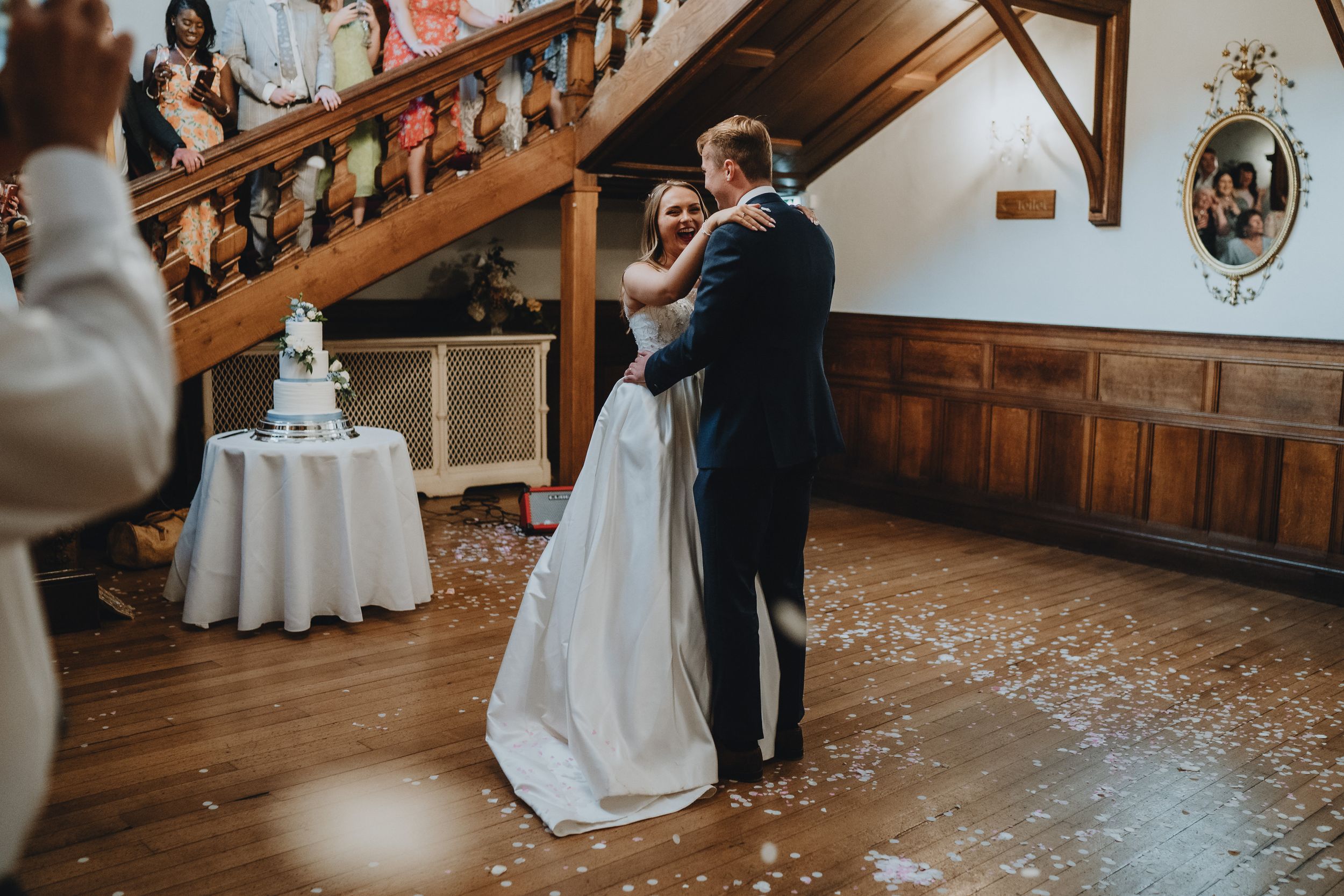 A couple shares their first dance at a rustic wedding reception venue with wooden walls and polished hardwood floors.