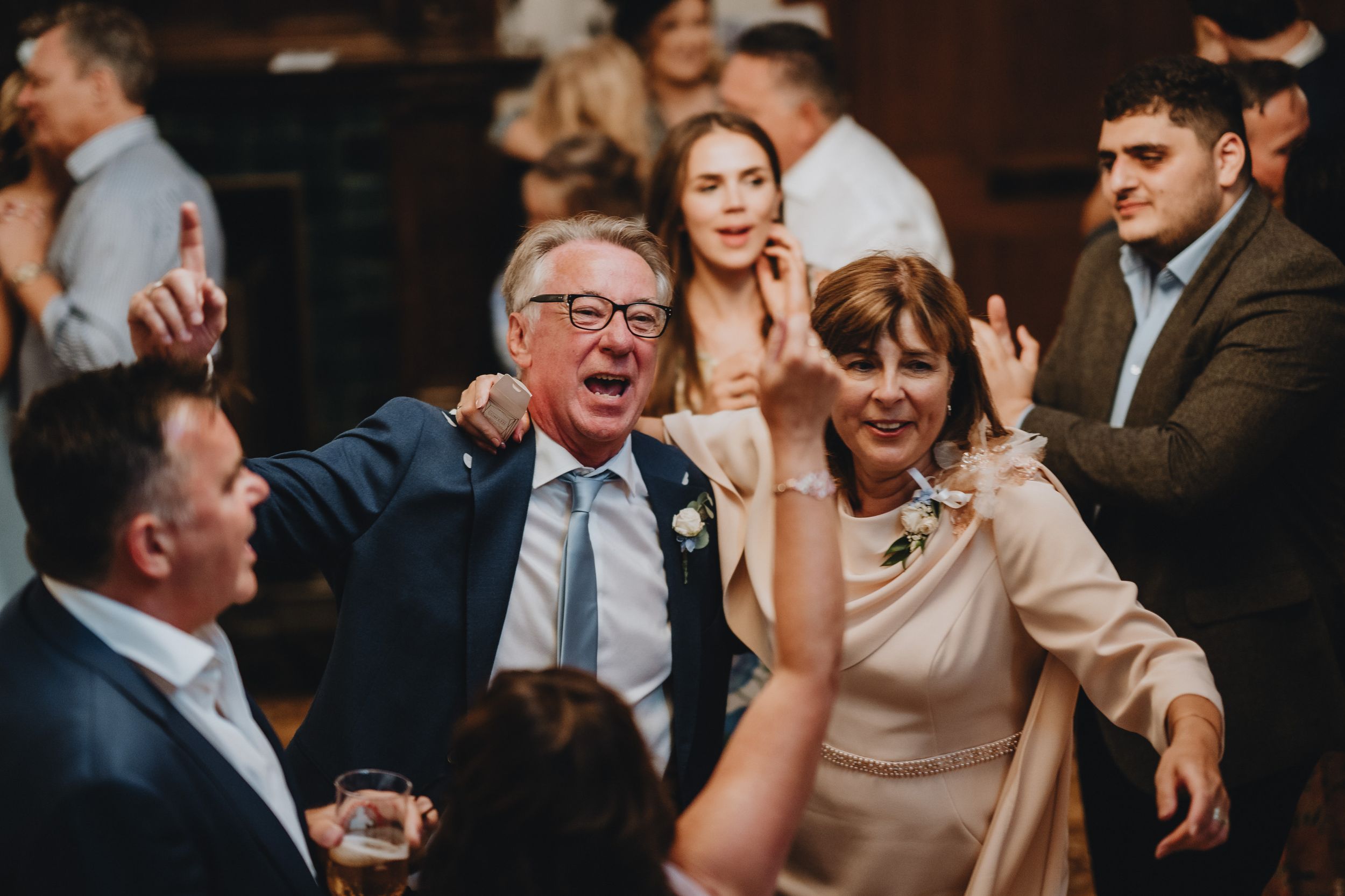 Wedding guests sharing an animated laugh together during a reception celebration.