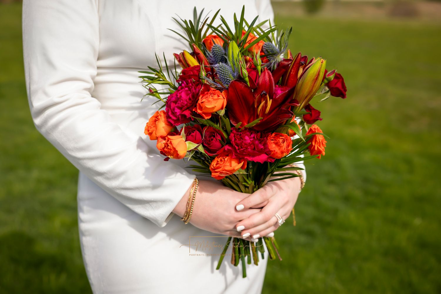 Bridal bouquet for wedding with jewel tone colors, red, orange, purple, with greenery