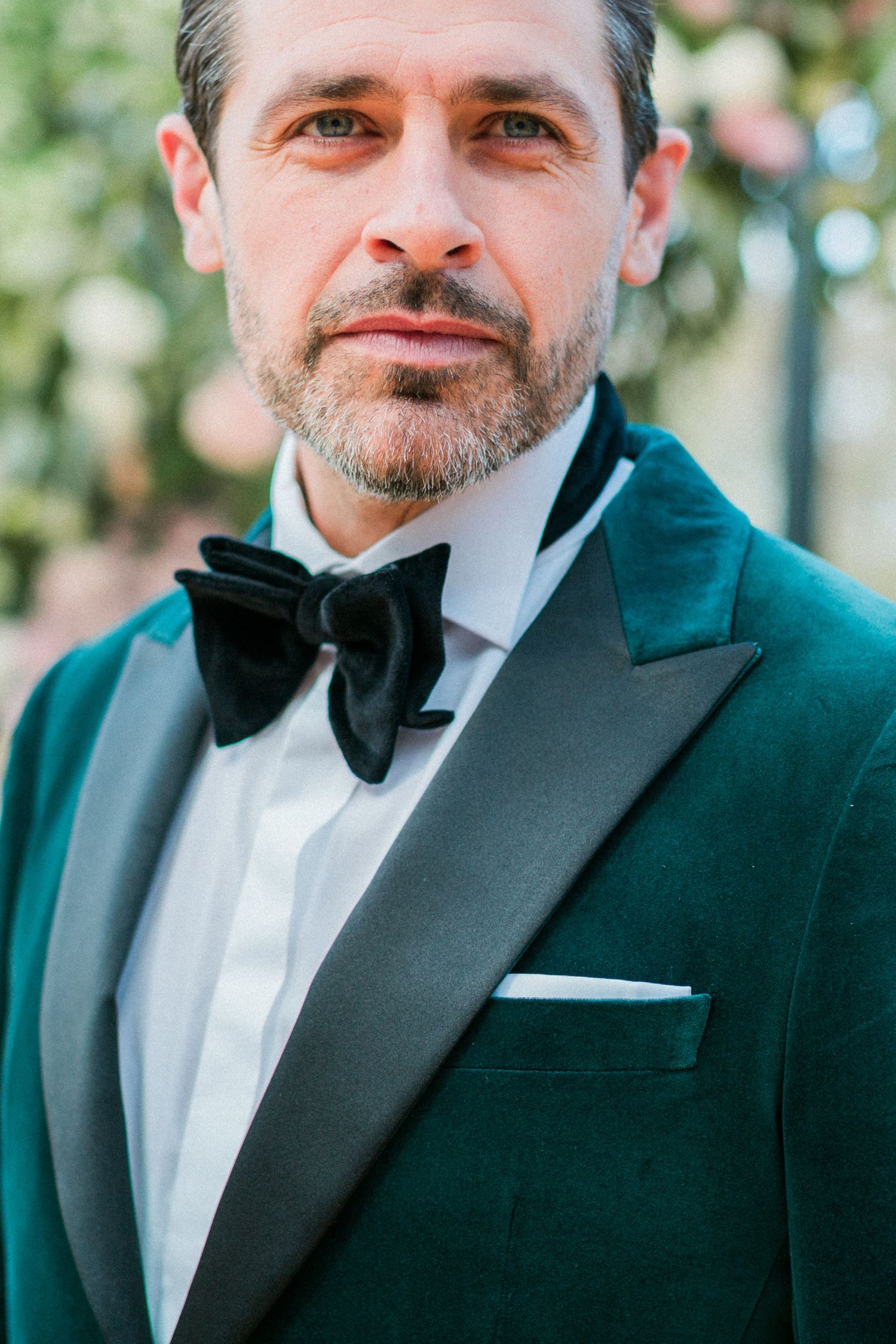 Groom in emerald green velvet tuxedo jacket with black bow tie, close up portrait at Sudeley Castle. Hayley Elizabeth photography