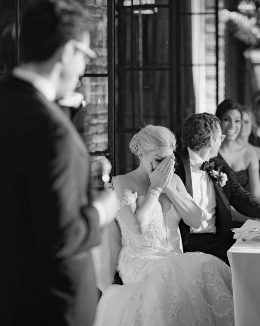 Black and white photo, bride, lace wedding dress covering her face with emotion during a candid reception moment, bowery hotel wedding