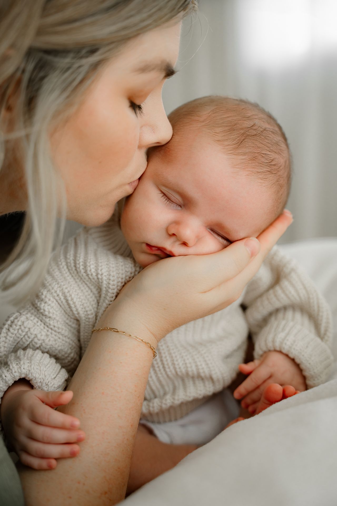 Tender moments captured between parent and infant in soft, natural lighting.