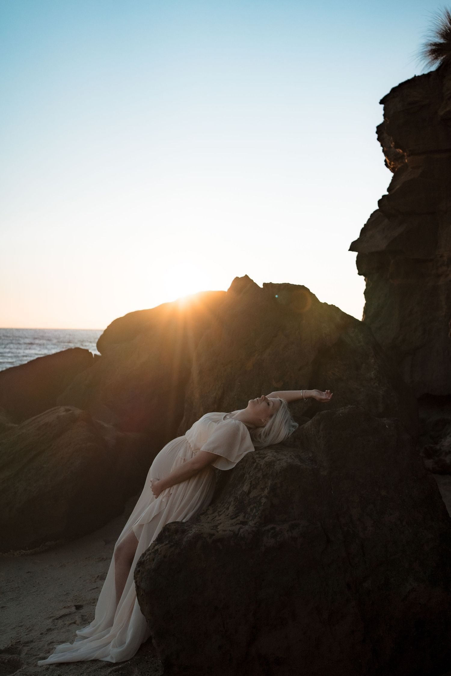 Gracefully laying on coastal rocks at sunset with ocean in background at Half Moon Bay, Black Rock