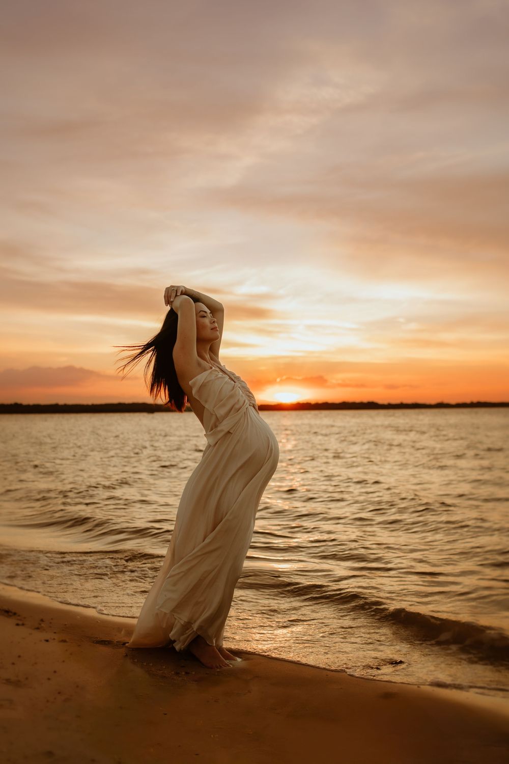 A series of dreamy silhouettes against a golden sunset shows a figure in white flowing dress along the waterfront.