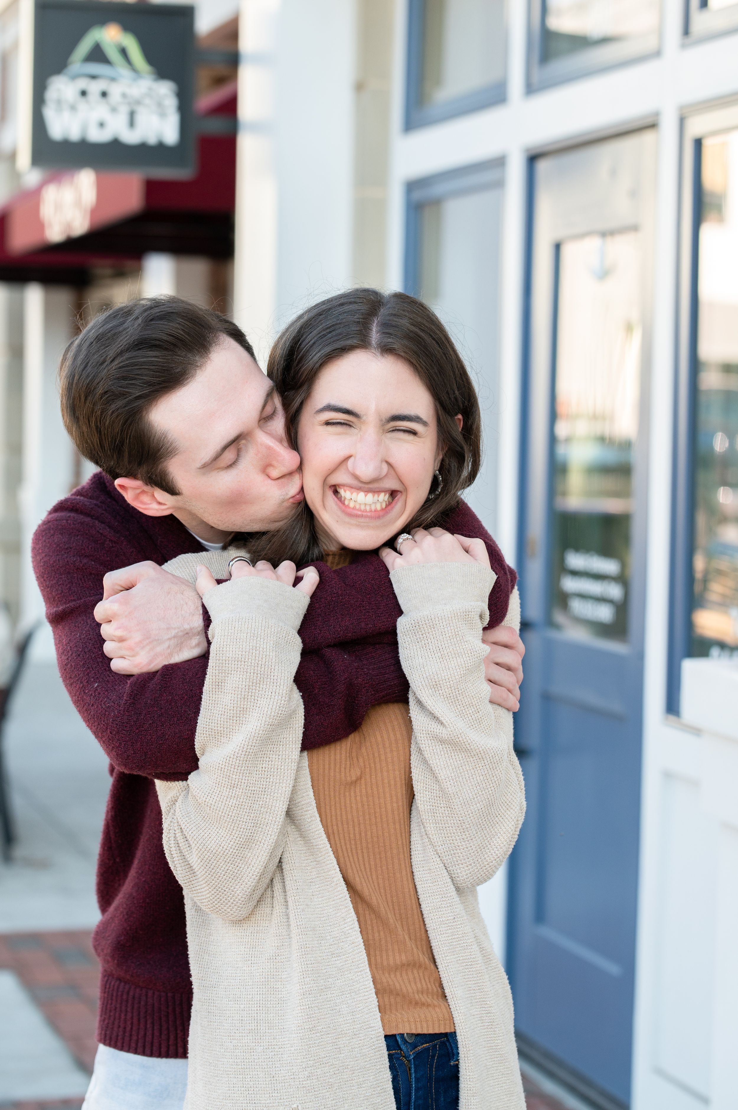 A joyful moment captured as a couple shares a playful embrace on a city sidewalk.