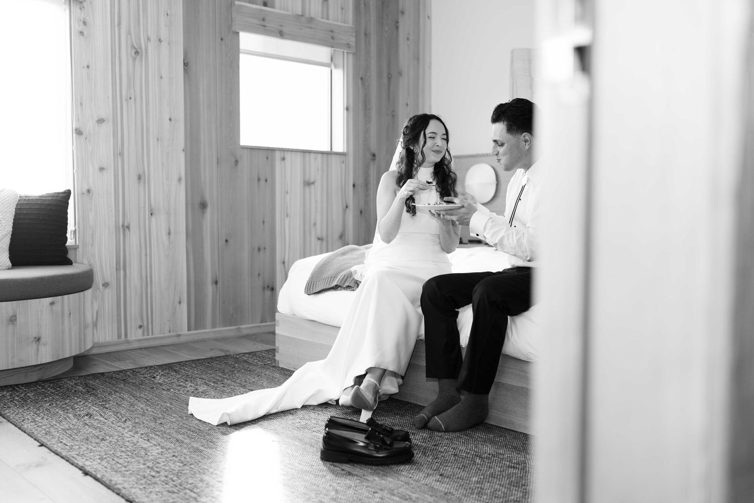 Black and white photograph of a couple sitting together on their wedding day in a Sea Ranch Lodge guest room.