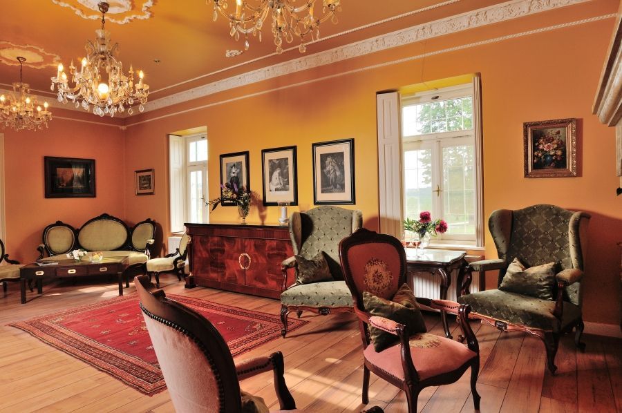 Elegant Victorian parlor with salmon-colored walls, antique furniture, crystal chandeliers and ornate Persian rugs.