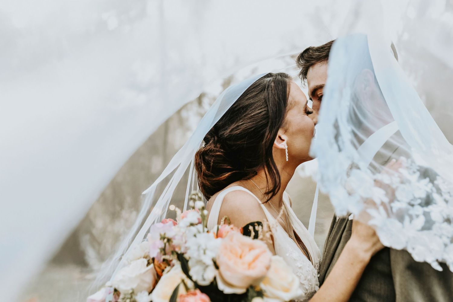bride and groom kiss under the brides veil a the lodge at the springs wedding venue in aubrey captured by april pinto photography