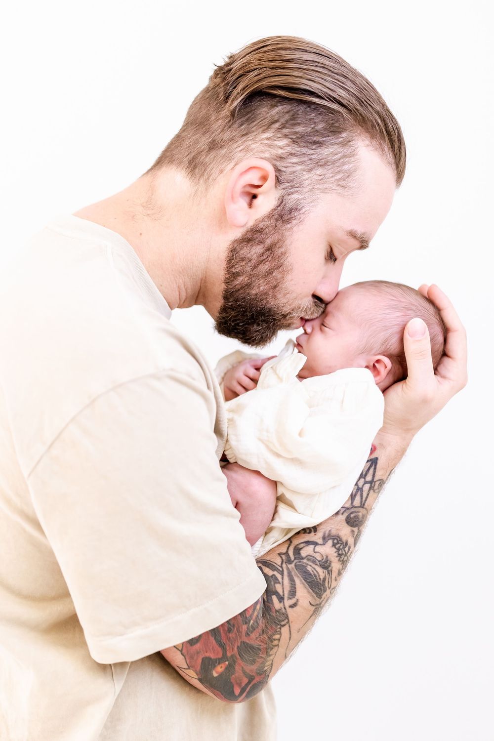 A tender moment between a parent and newborn baby against a white background.
