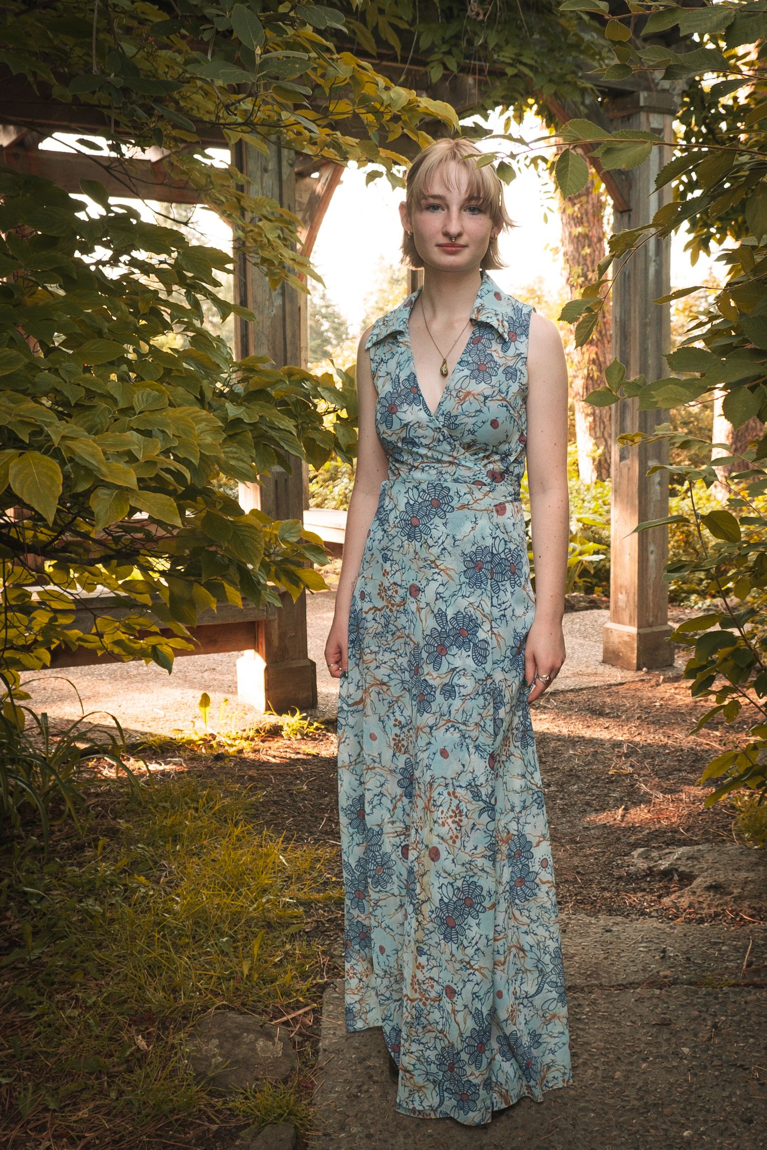 Long floral blue maxi dress photographed in garden setting with natural sunlight.