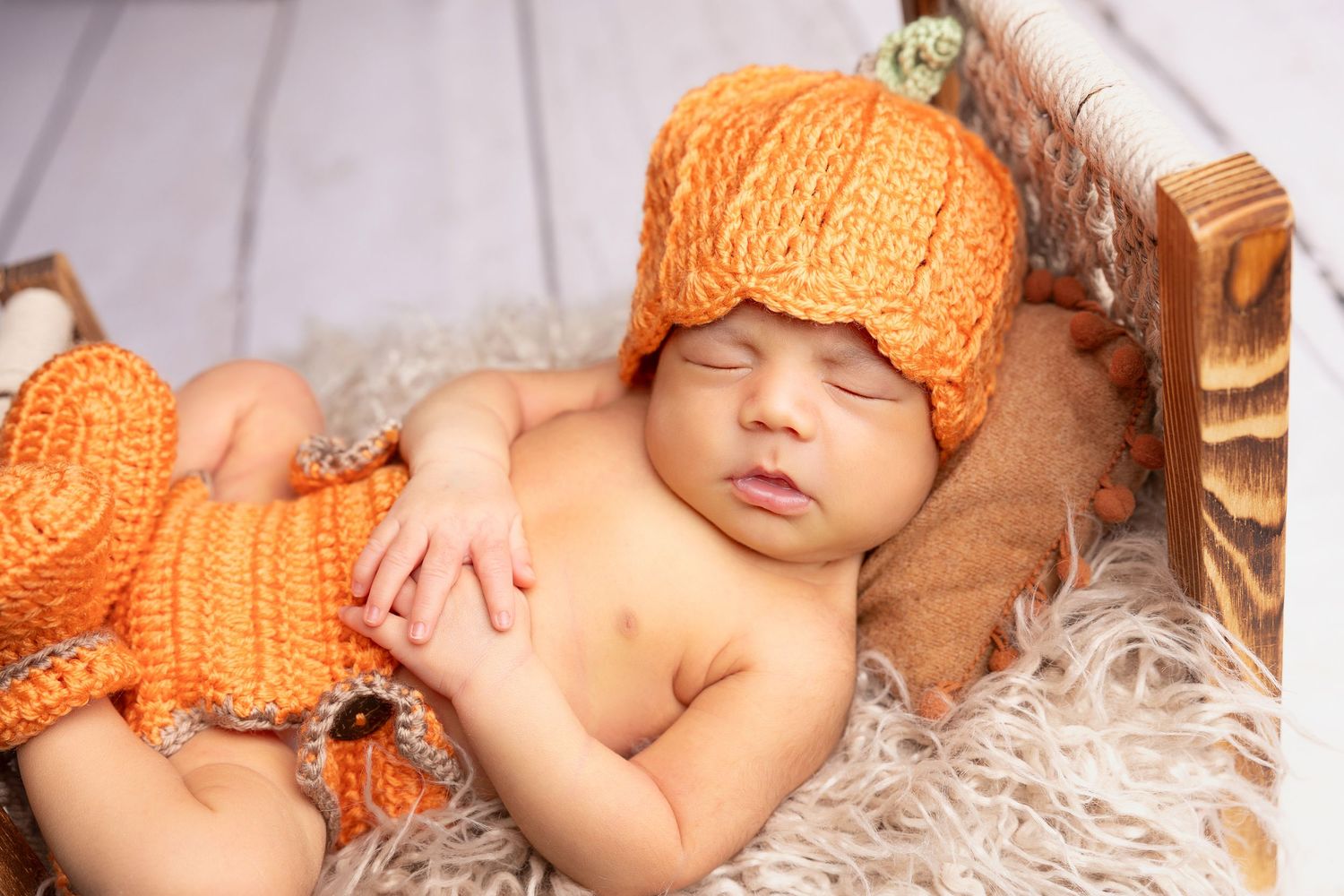 A sleeping baby on a white wooden bed with fur bedding surrounded by bright yellow sunflowers.