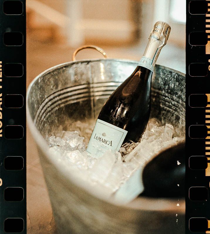 A bottle of Carmina wine chilling in an ice bucket with a vintage 35mm frame shot at Christ Church Fox Chapel near pittsburgh PA wedding.