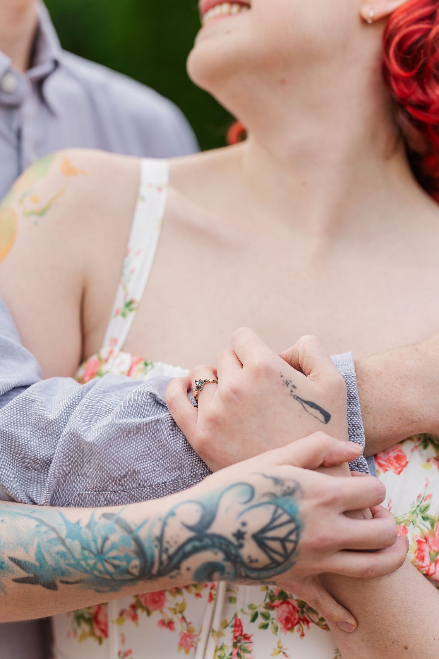 Close-up of tattooed arms embracing in a romantic moment while wearing floral dress and grey shirt at Cantigny Park