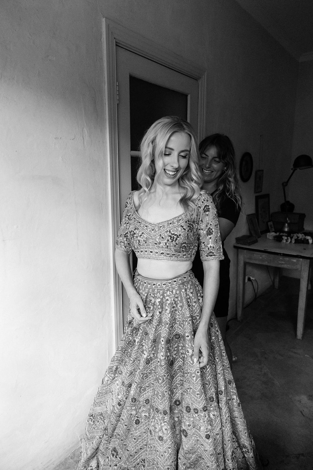 Black and white photo of a two-piece embroidered lace wedding lehenga outfit with crop top and full skirt.