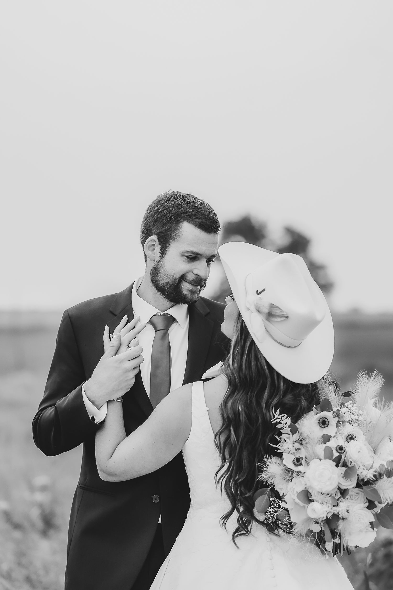 a groom holds the hand of his bride as he gazes into her eyes and smiles at her during their wedding photos the madelyn wedding venue