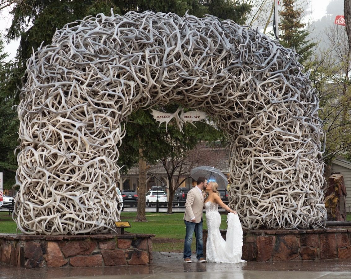 rainy day with a couple standing under antler arch in Wyoming