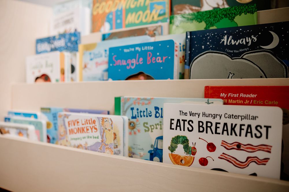 Children's books displayed on a shelf including The Very Hungry Caterpillar and other popular titles.
