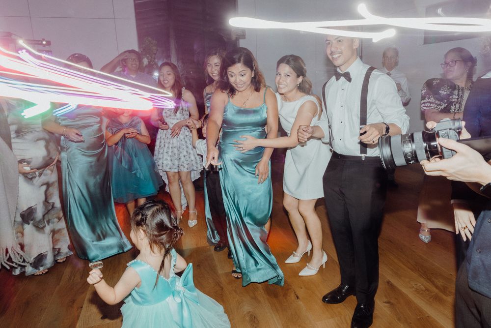 Wedding guests dance and celebrate on a wooden dance floor captured by Apertured Media Auckland Wedding Photographer.