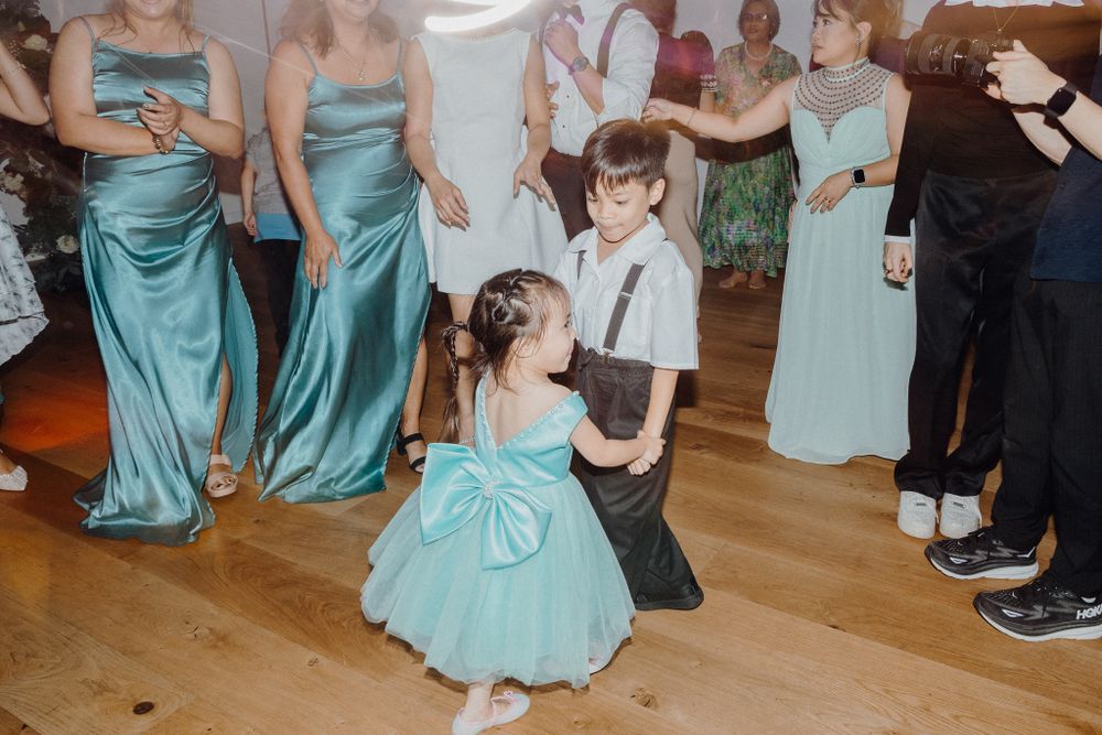 Dancers in turquoise bridesmaid dresses and formal wear enjoy a reception captured by Apertured Media Auckland Wedding Photographer.