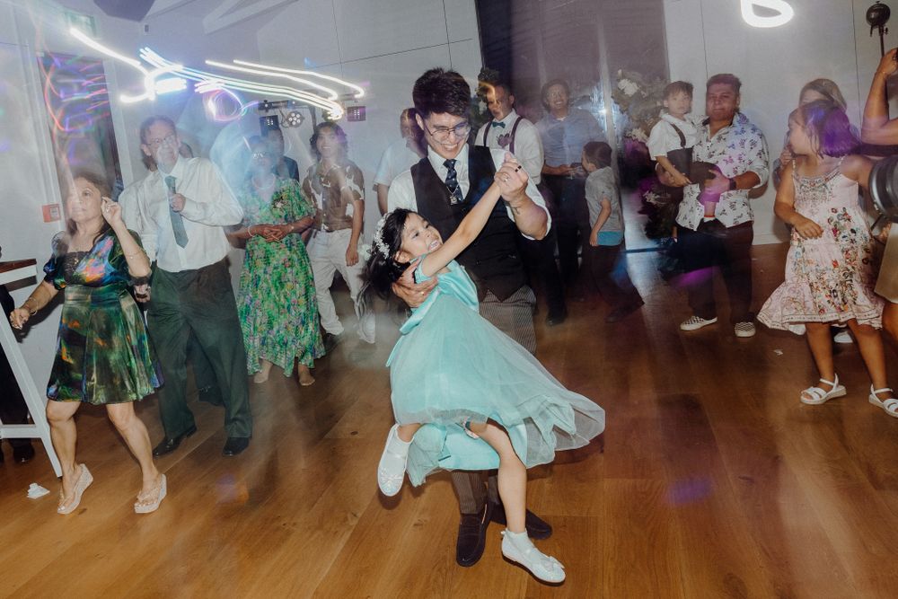 Dancers in vintage-style clothing move energetically captured by Apertured Media Auckland Wedding Photographer.