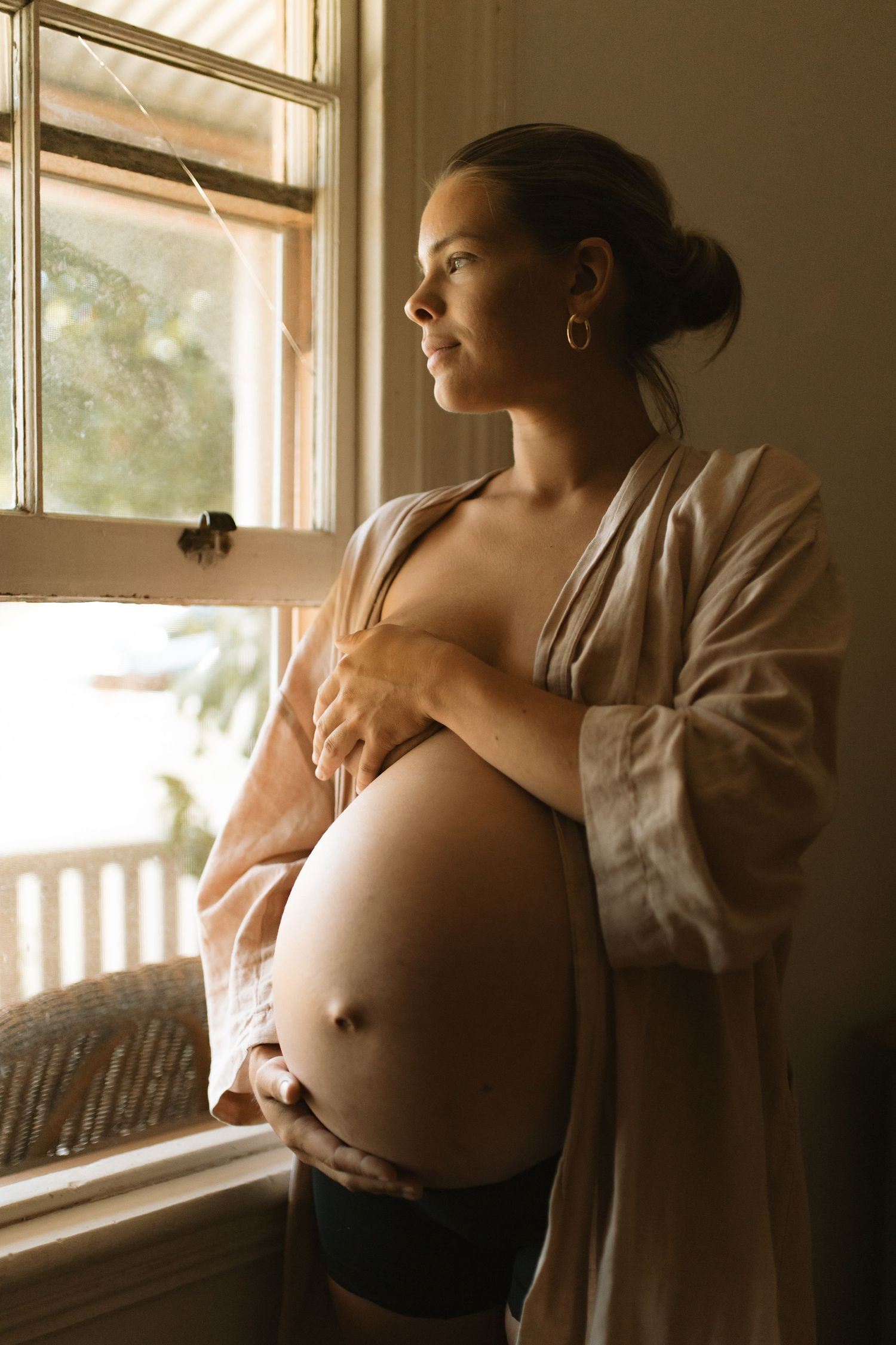 Maternity in home shoot mother looking out of her bedroom window