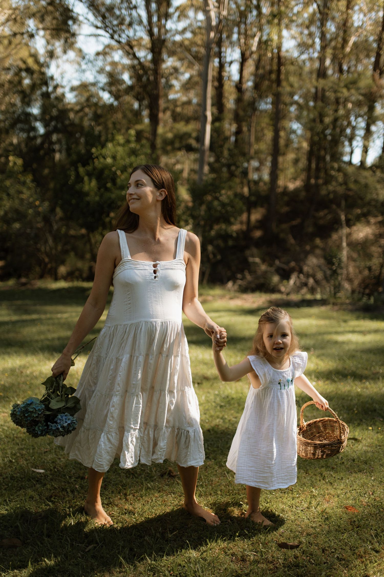 Pregnant mother and her little girl collecting flowers in their garden