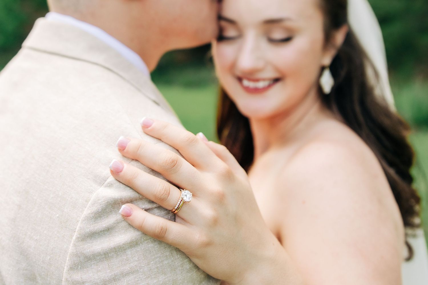 A close-up of clasped hands showing an engagement ring during an intimate outdoor photo session.
