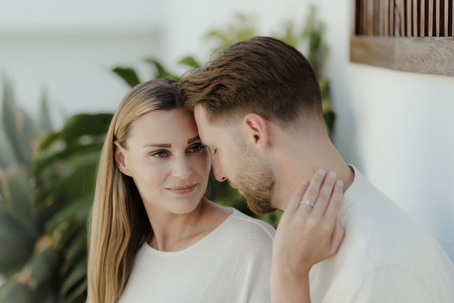 Romantic couple shares intimate moments in a dreamy summer photoshoot with palm trees in the background.