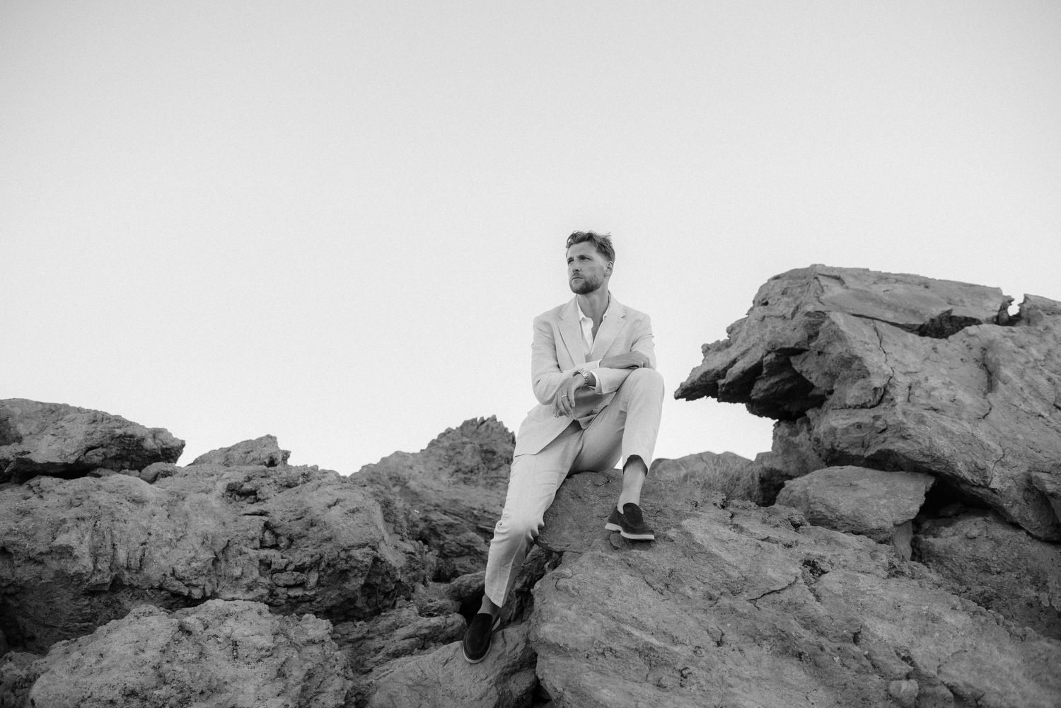 Black and white panoramic sequence showing a person climbing over rocky terrain in six progressive stages.