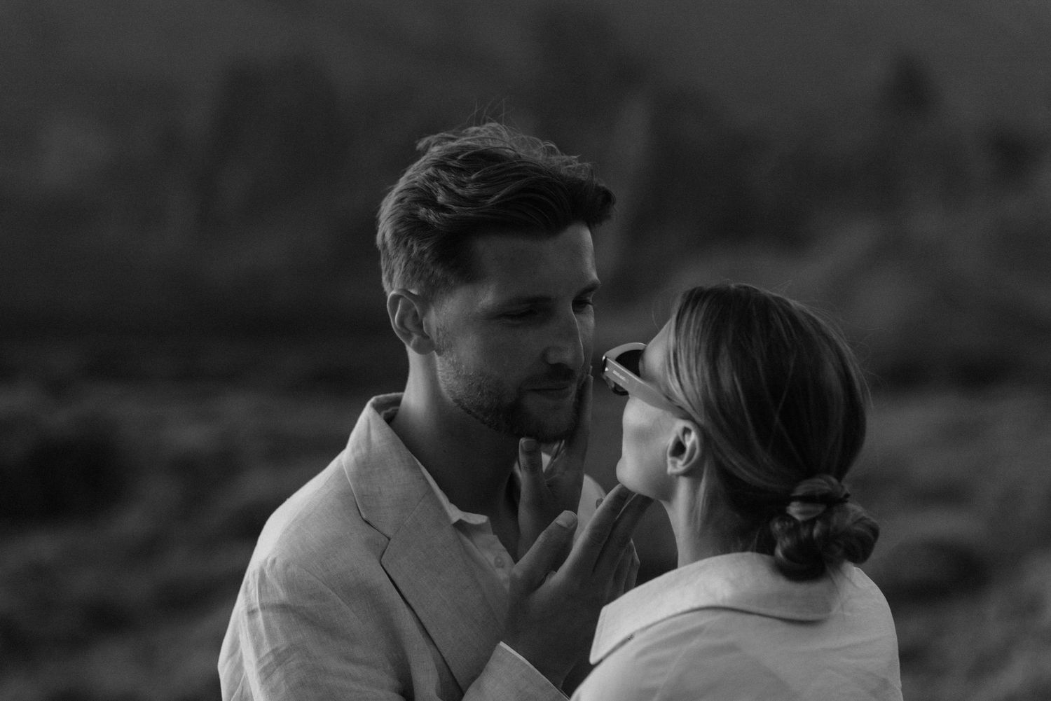 Intimate black and white portrait of a couple sharing a tender moment outdoors.