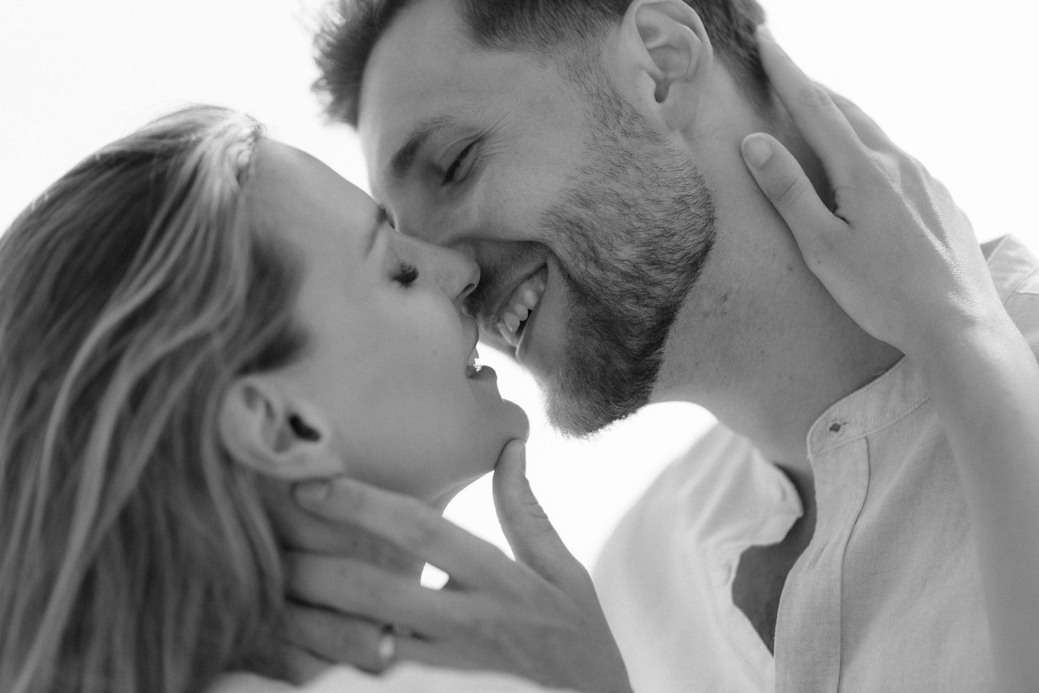 A romantic black and white close-up portrait of an intimate couple about to kiss.